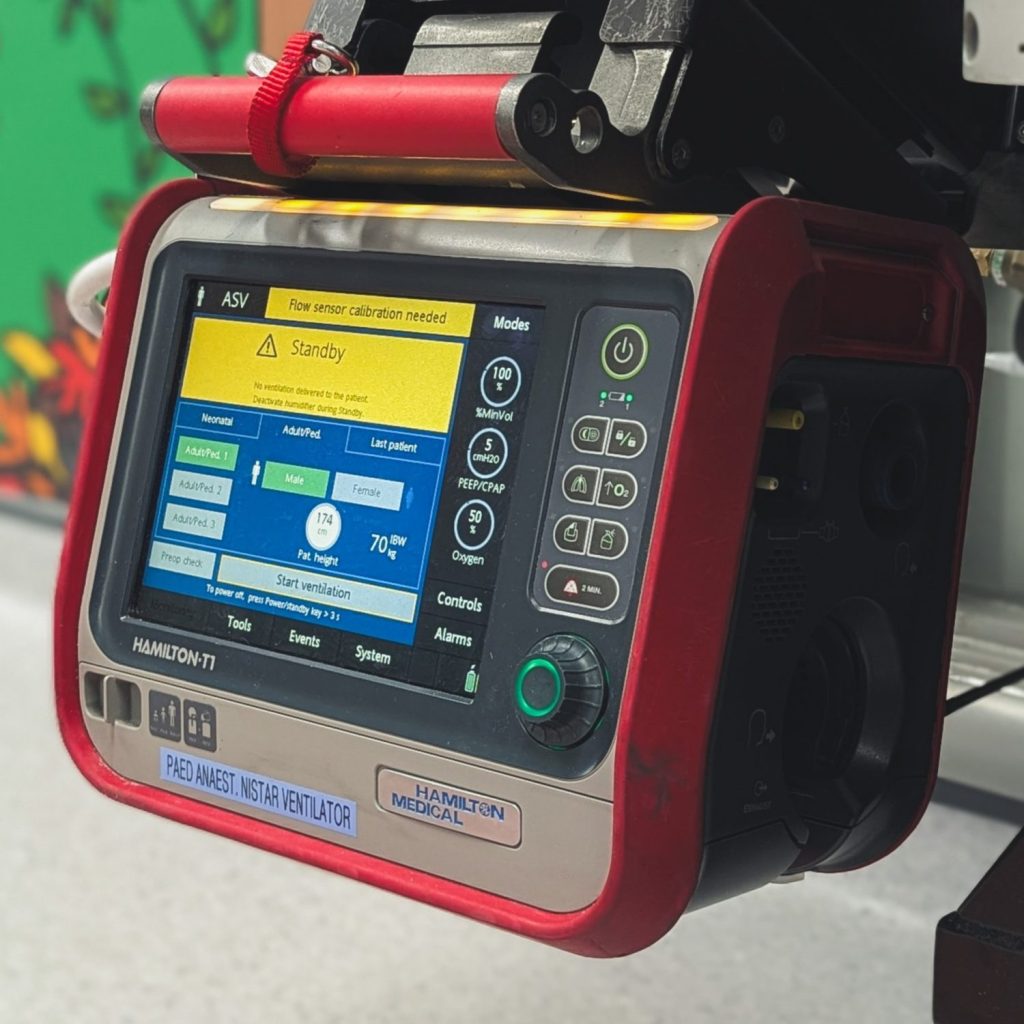Hamilton T1 Ventilator hanging on bracket on paediatric transport trolley